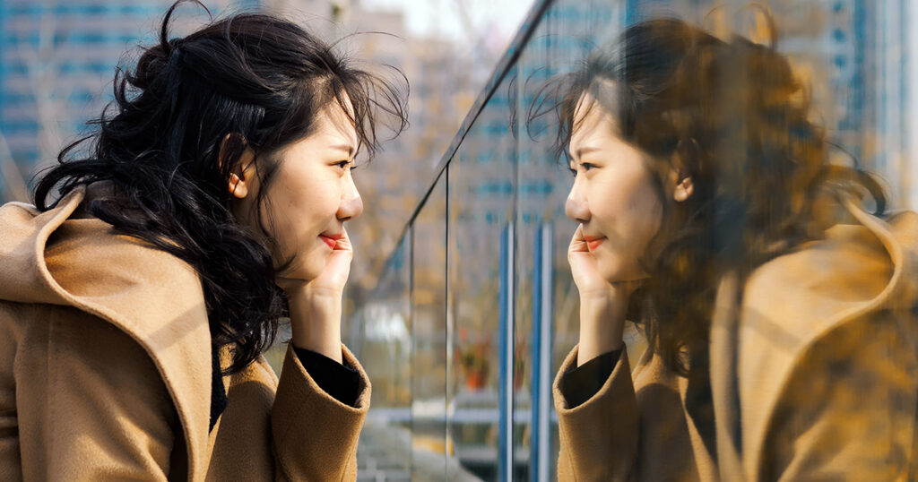 A woman smiles at her reflection.