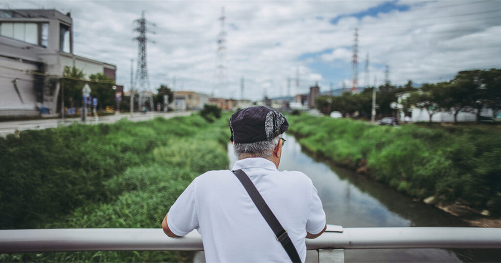 An older man leans against a railing.